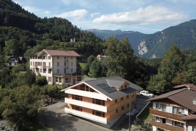 Altes Hotel und Holzneubau in Berglandschaft