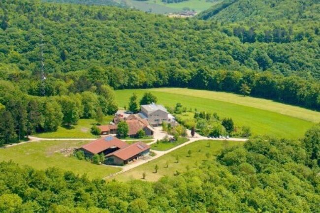 Hofgebauede in gruener huegellandschaft